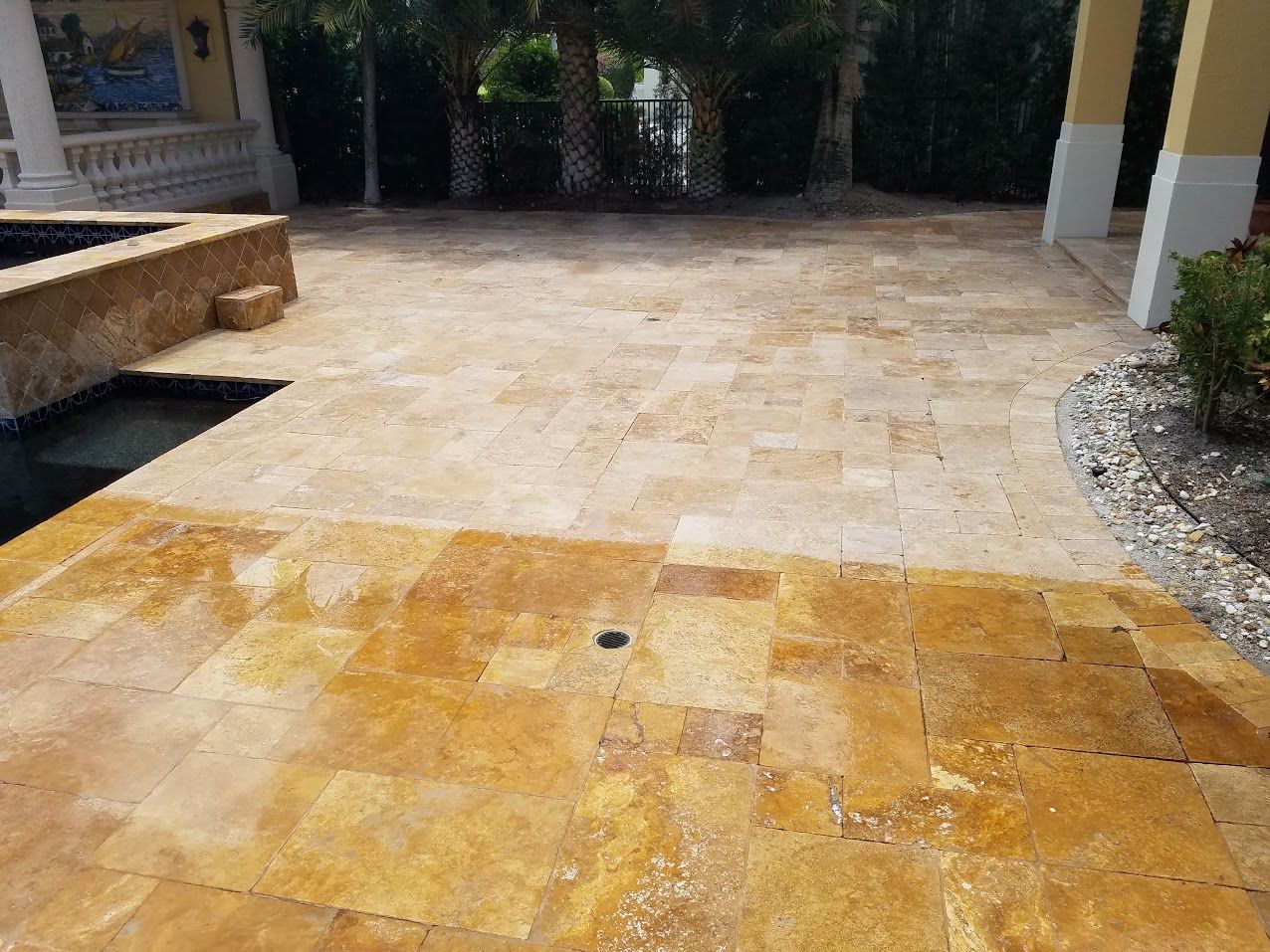 Stone patio with yellow-tiled foreground, bordered by a bench on the left and plants on the right