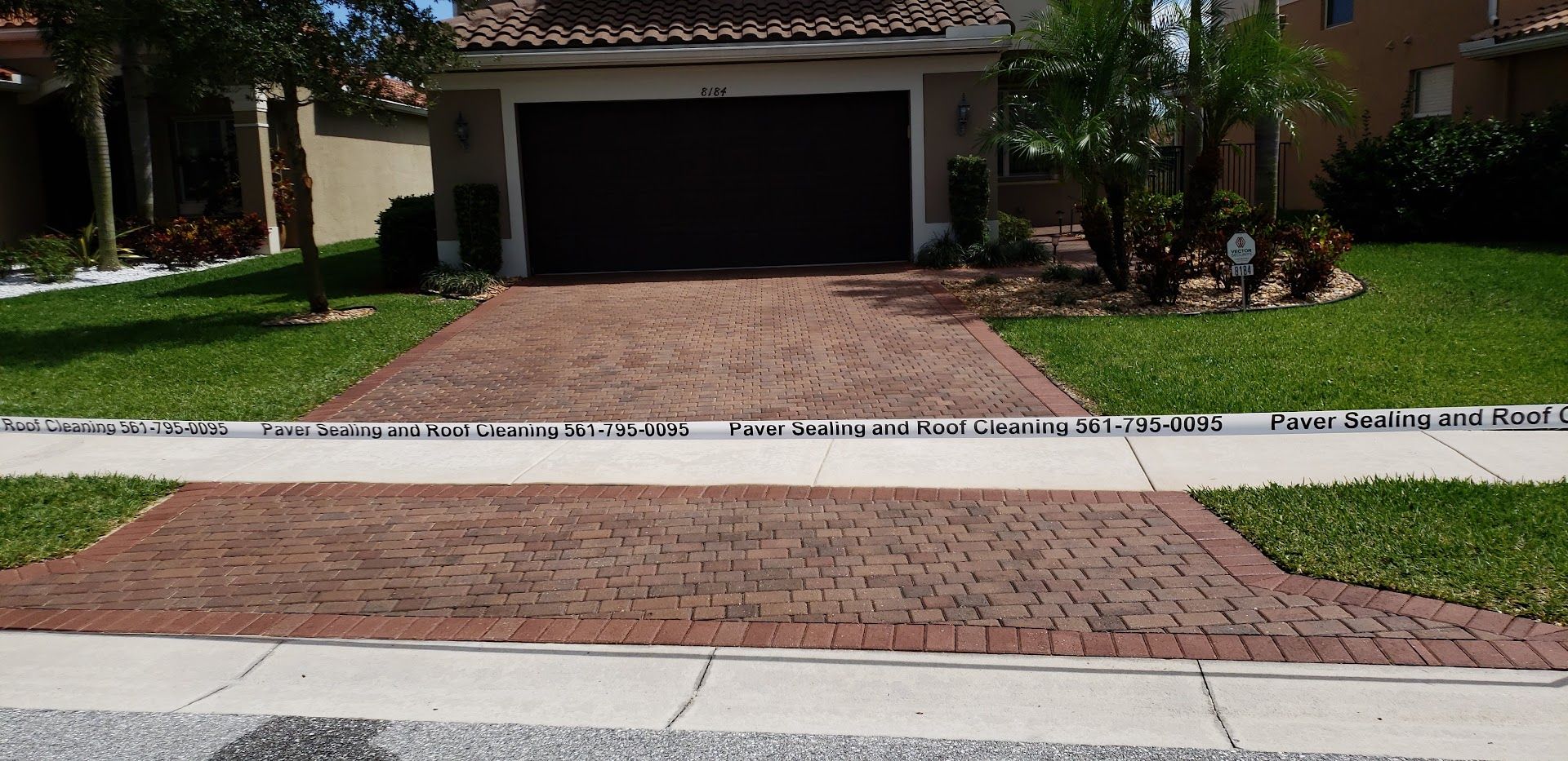 Brick driveway leading to a garage, with a sidewalk and landscaped front lawn.