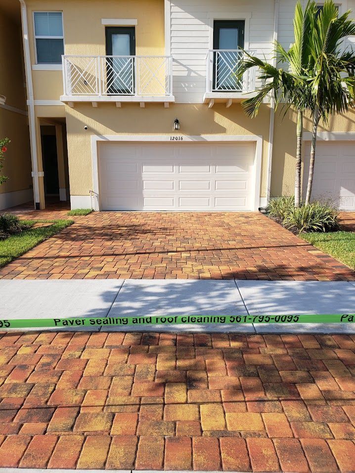 Two-story townhouse with white garage, brick driveway, and palm tree in front