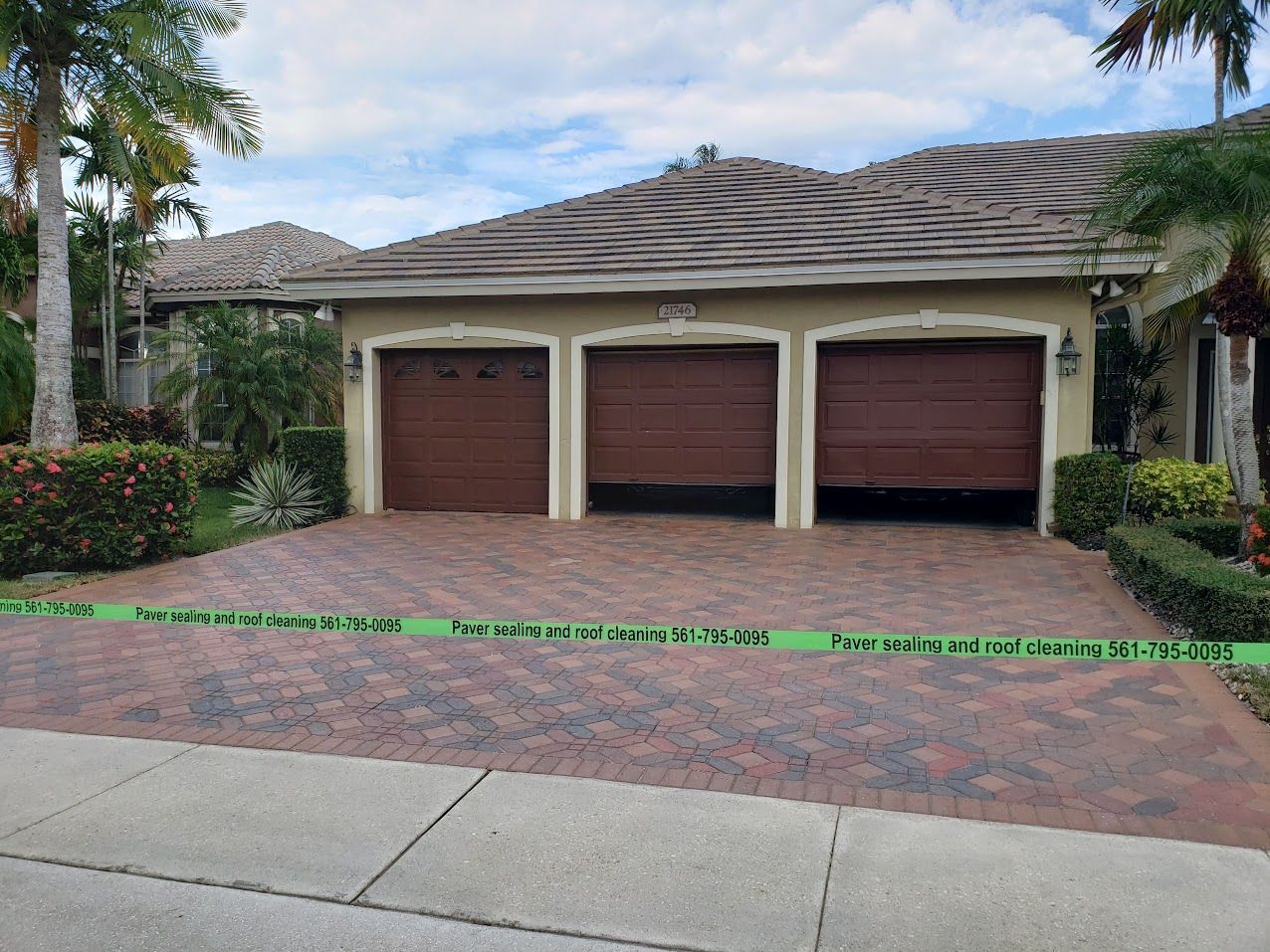 Three-car garage with brown doors and a brick driveway in a landscaped suburban home setting