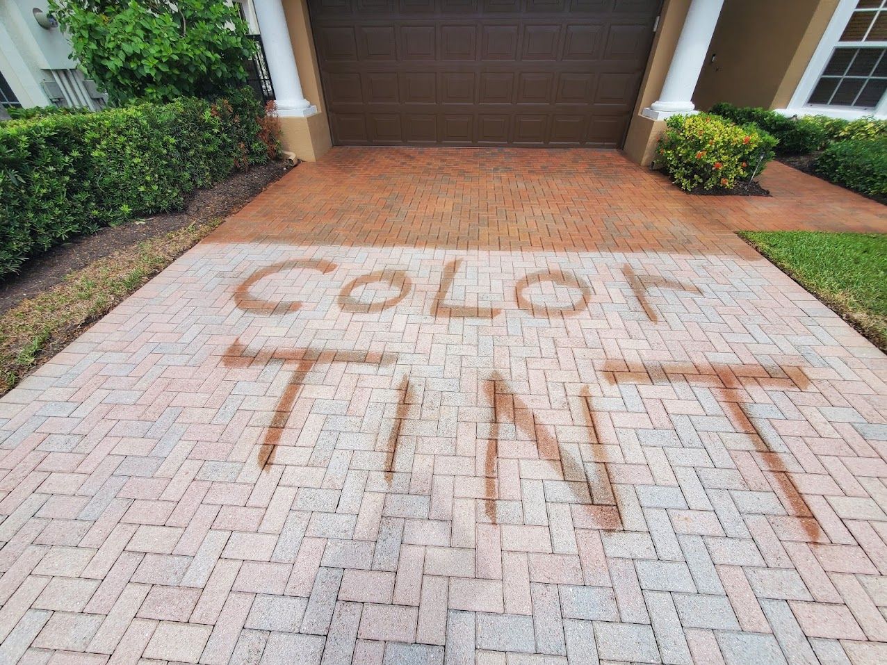 “TINT” spray-painted in large letters on a driveway in front of a garage.