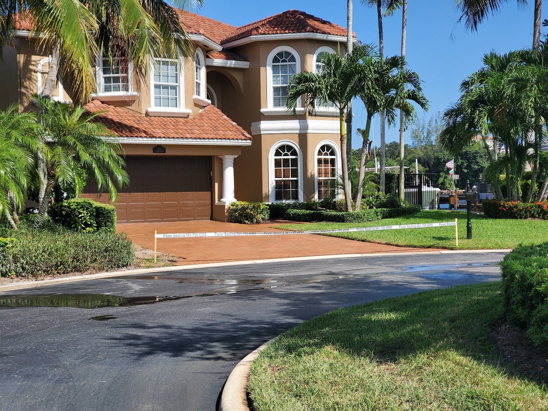 Large Mediterranean-style house with red tile roof, palm trees, and a curved driveway in front