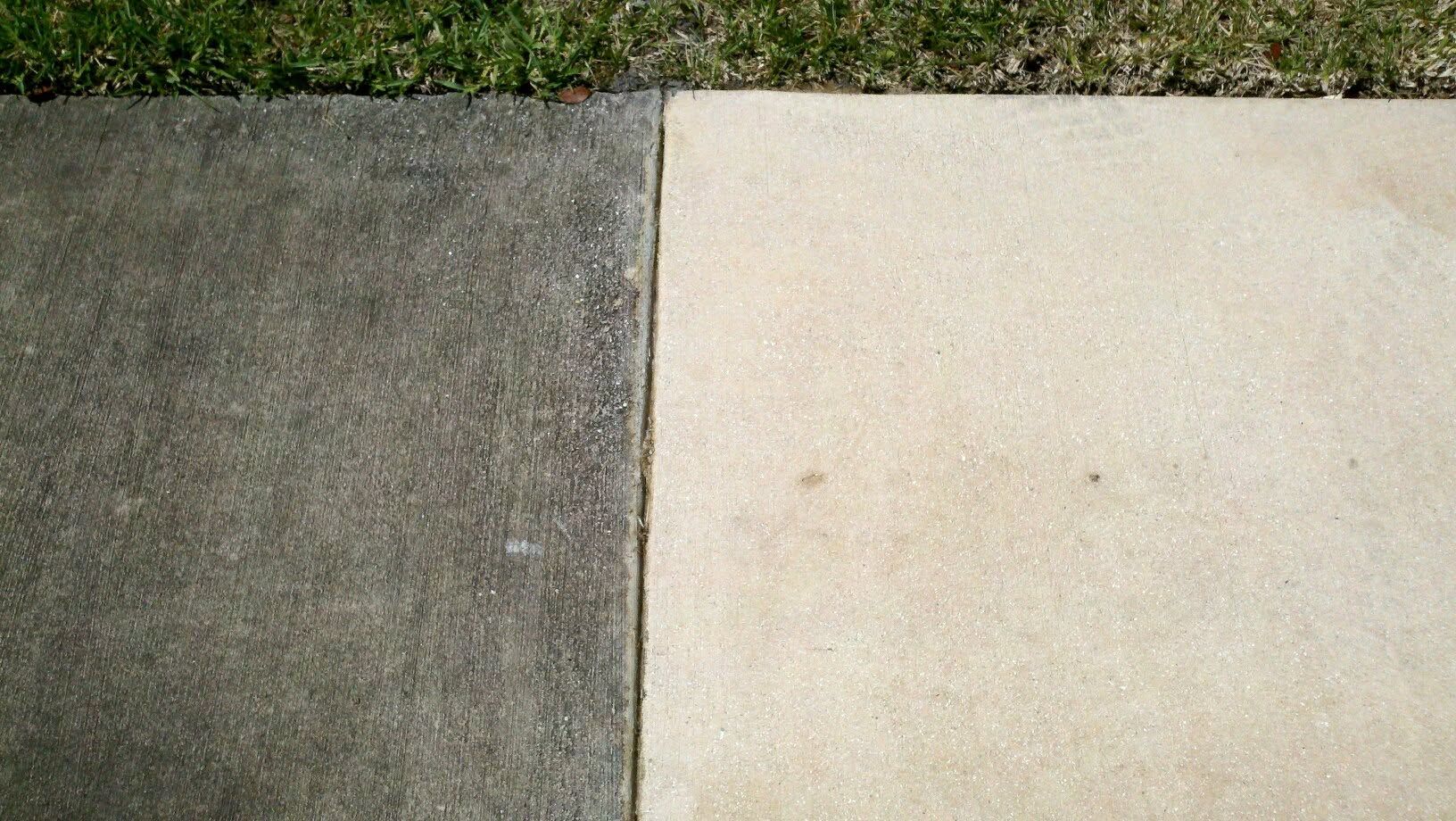 Concrete sidewalk slabs in gray and beige beside a strip of grass