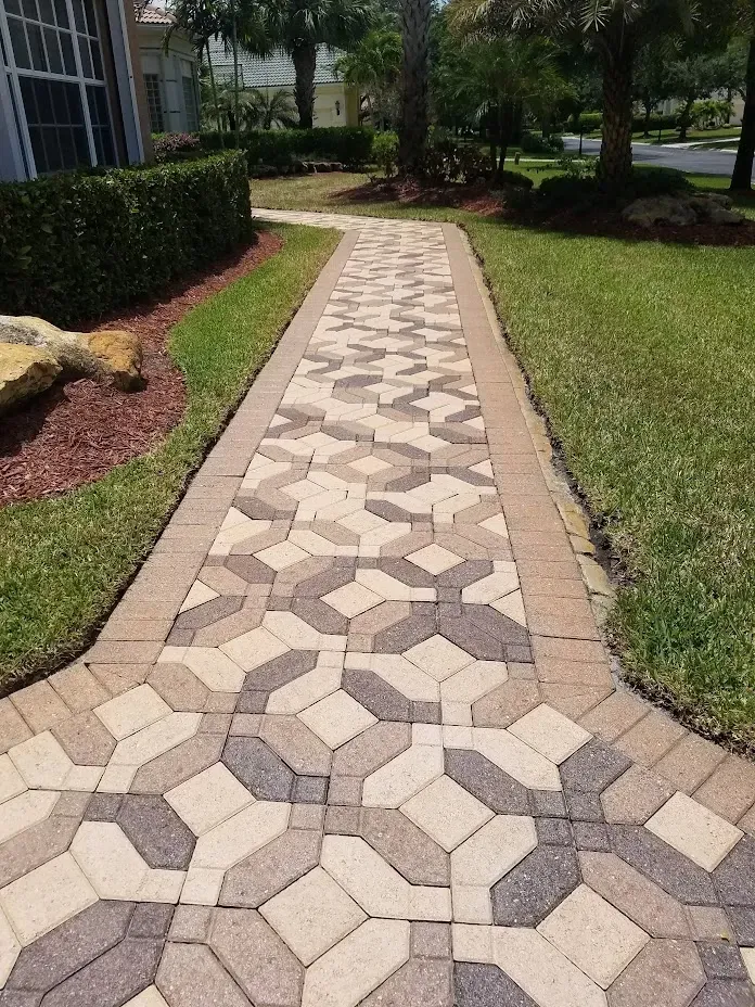 Curved stone walkway with geometric pavers through a grassy residential garden