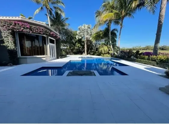 Modern backyard pool with palm trees and a shaded patio under a bright blue sky