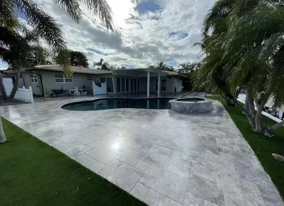 Modern backyard patio with a swimming pool, hot tub, and palm trees under a cloudy sky