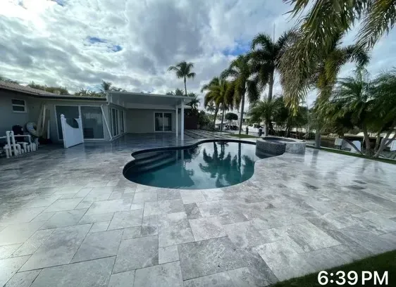 Courtyard pool with palm trees beside a building at dusk, with lounge chairs and a cloudy sky.