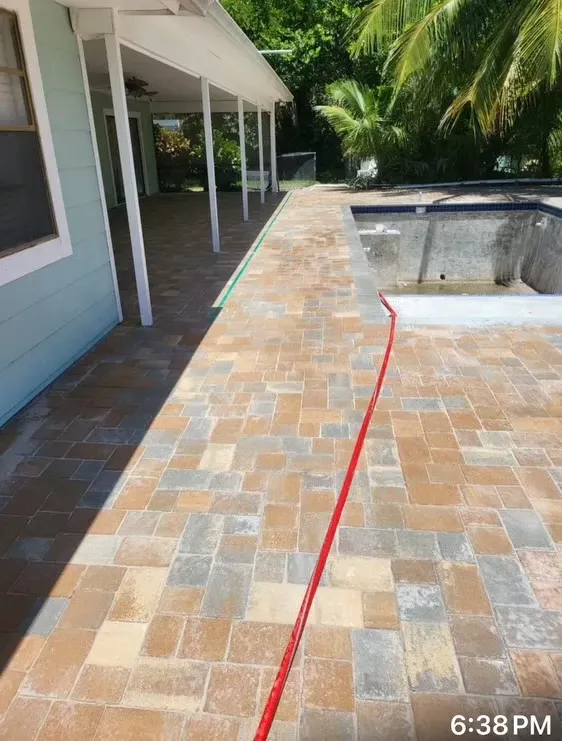 Backyard patio with stone pavers, pool edge, and a red line marking a crack in the walkway