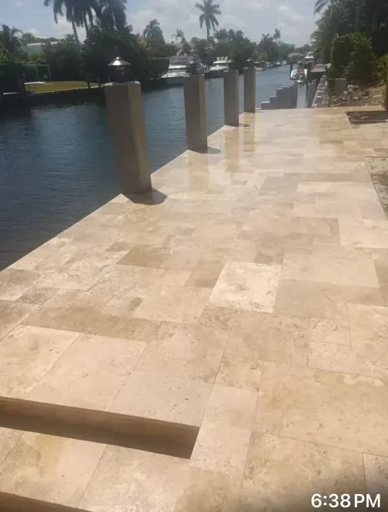 Stone walkway beside a calm canal with columns and palm trees at dusk