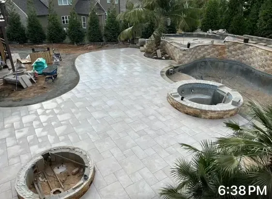 Backyard patio with newly laid stone paving, built-in fire pits, and landscaping under construction