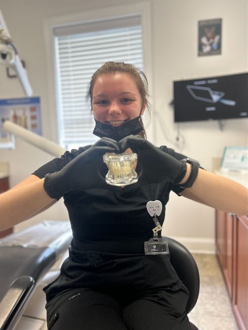 Una mujer en un consultorio dental haciendo forma de corazón con sus manos.
