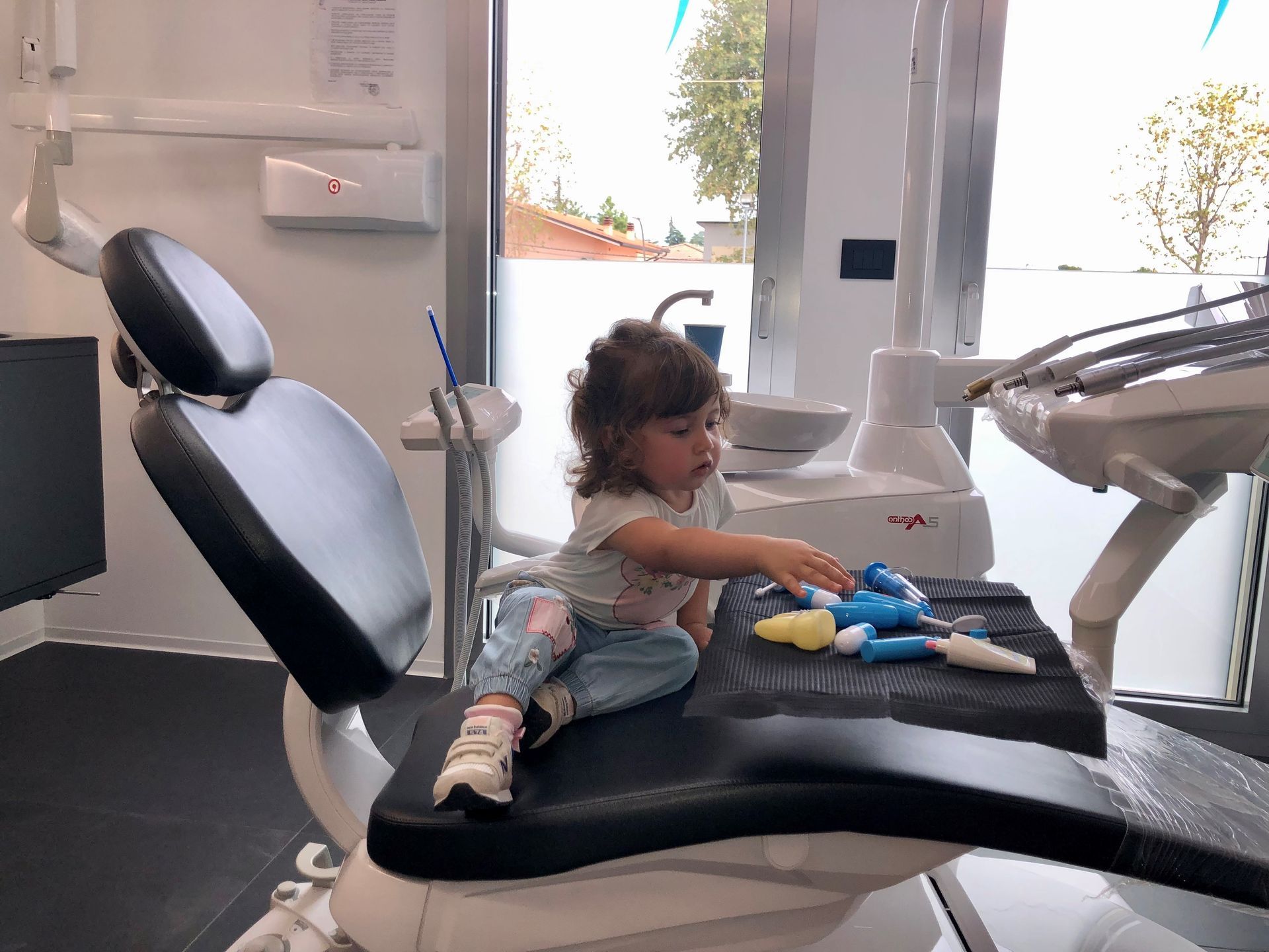 bambina che gioca seduta sopra una poltrona dentistica