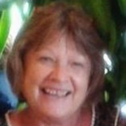 Smiling woman with brown hair against a green leafy background