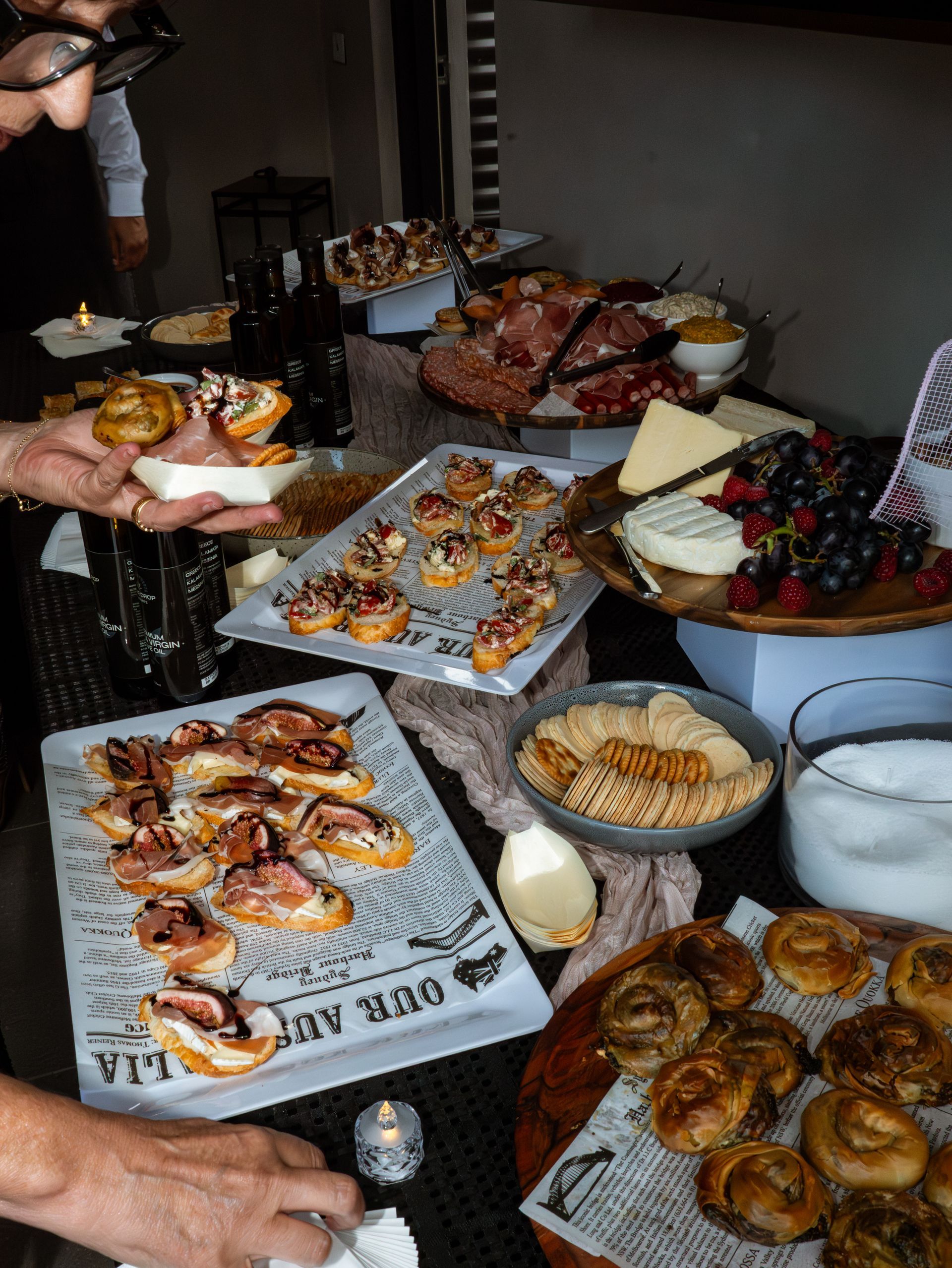 Dessert buffet table with pastries, cakes, and cookies, with people serving themselves at a party