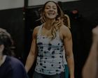 Smiling woman in a gray tank top standing in a gym or workout studio