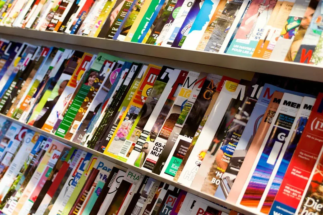 Tijdschriften in een kast; verschillende kleuren en titels.