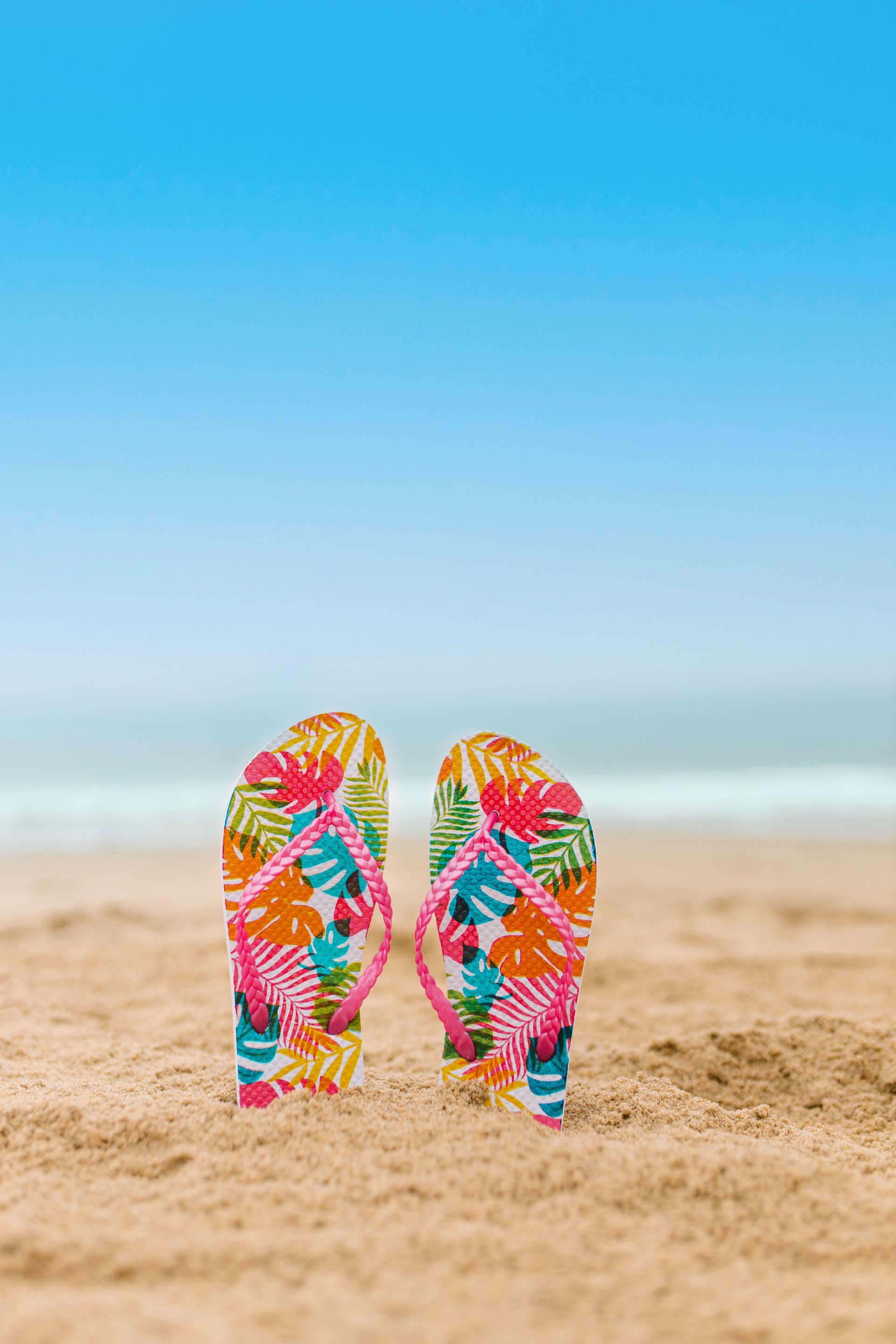 Pair of slippers resting in the sand beside the ocean in Hawaii, symbolizing island business growth.