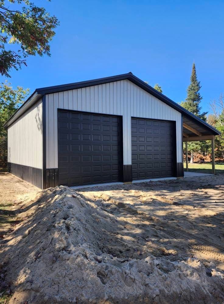 Two-bay metal garage with black doors and white walls; a small, covered porch is on the right.
