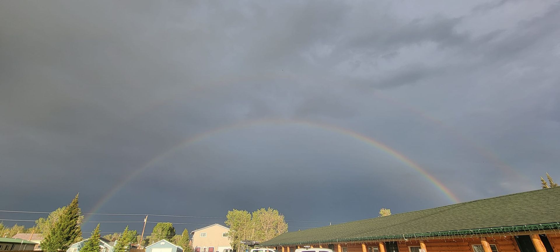 There is a double rainbow in the sky over a building.