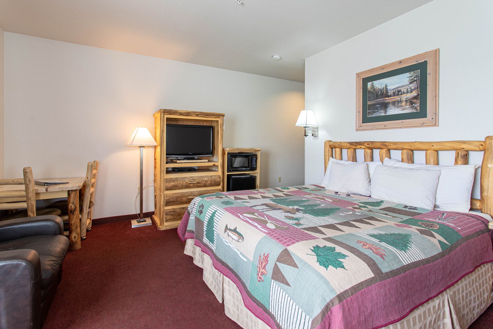 A hotel room with a king size bed , television , table and chairs.