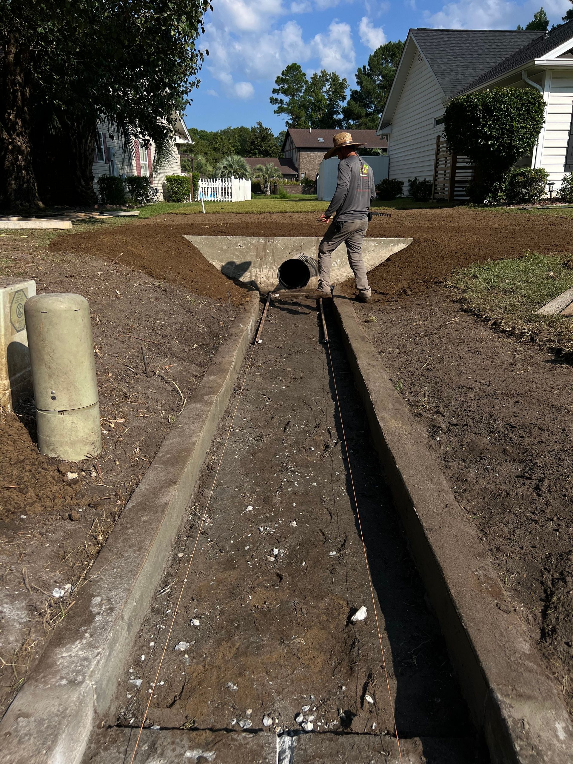 Worker standing in a trench beside a dug-up street near houses
