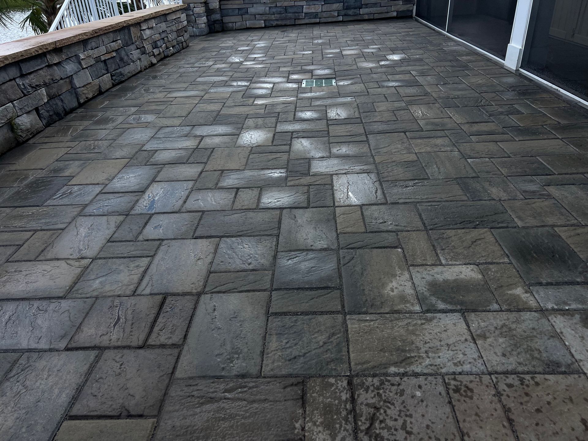 Stone-paved outdoor patio with a low stone wall and railing along the edge