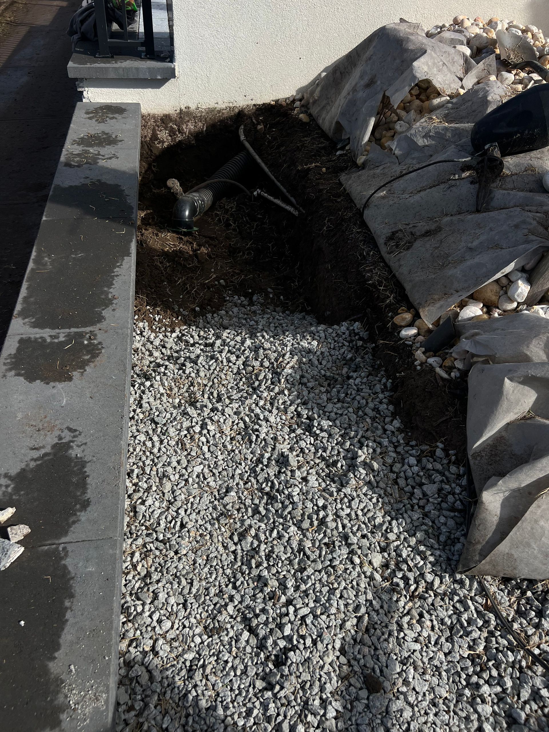 Collapsed curb and broken asphalt over gravel beside a sidewalk
