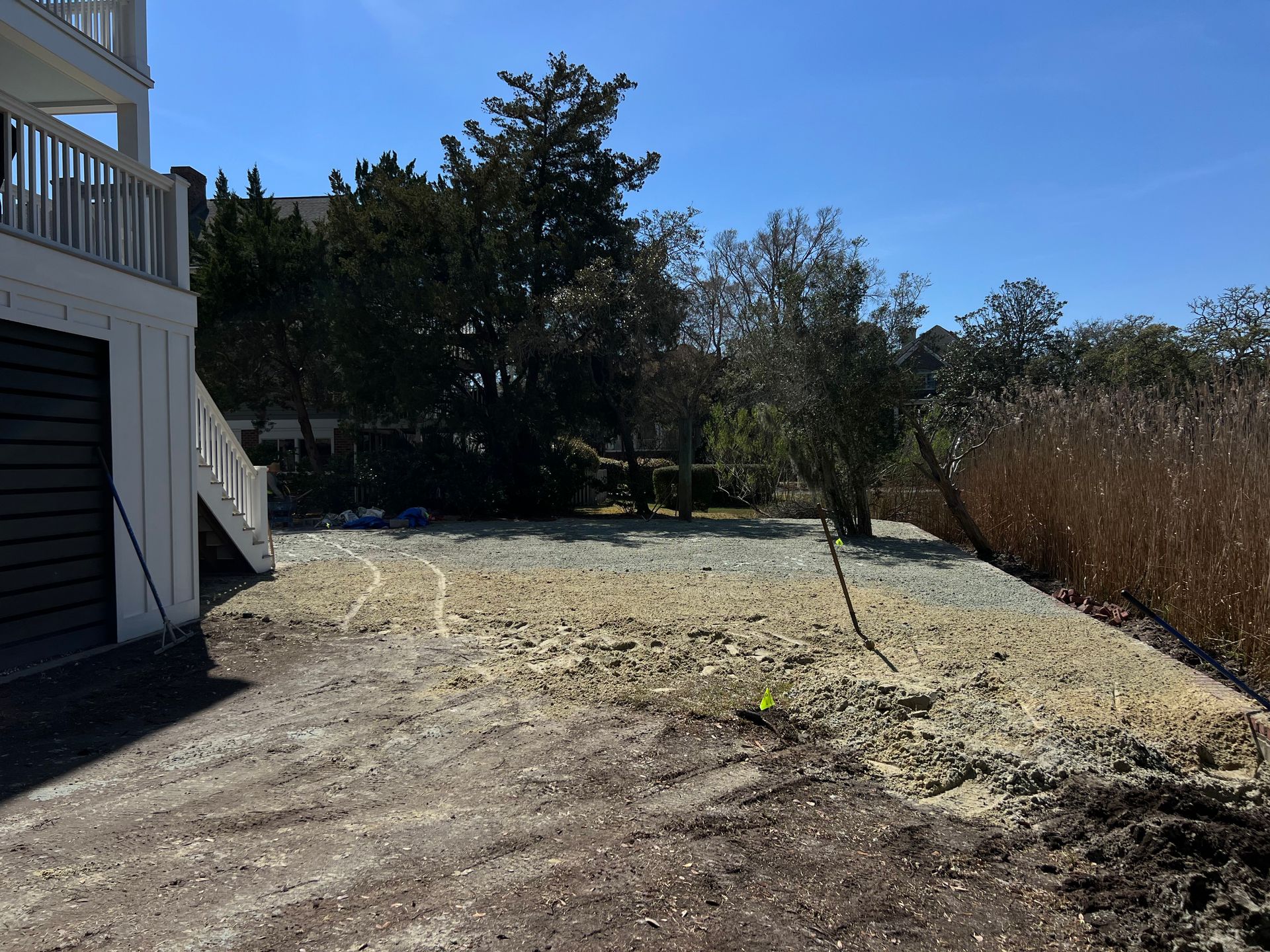 Backyard with a wooden deck, bare ground, trees, and a clear blue sky