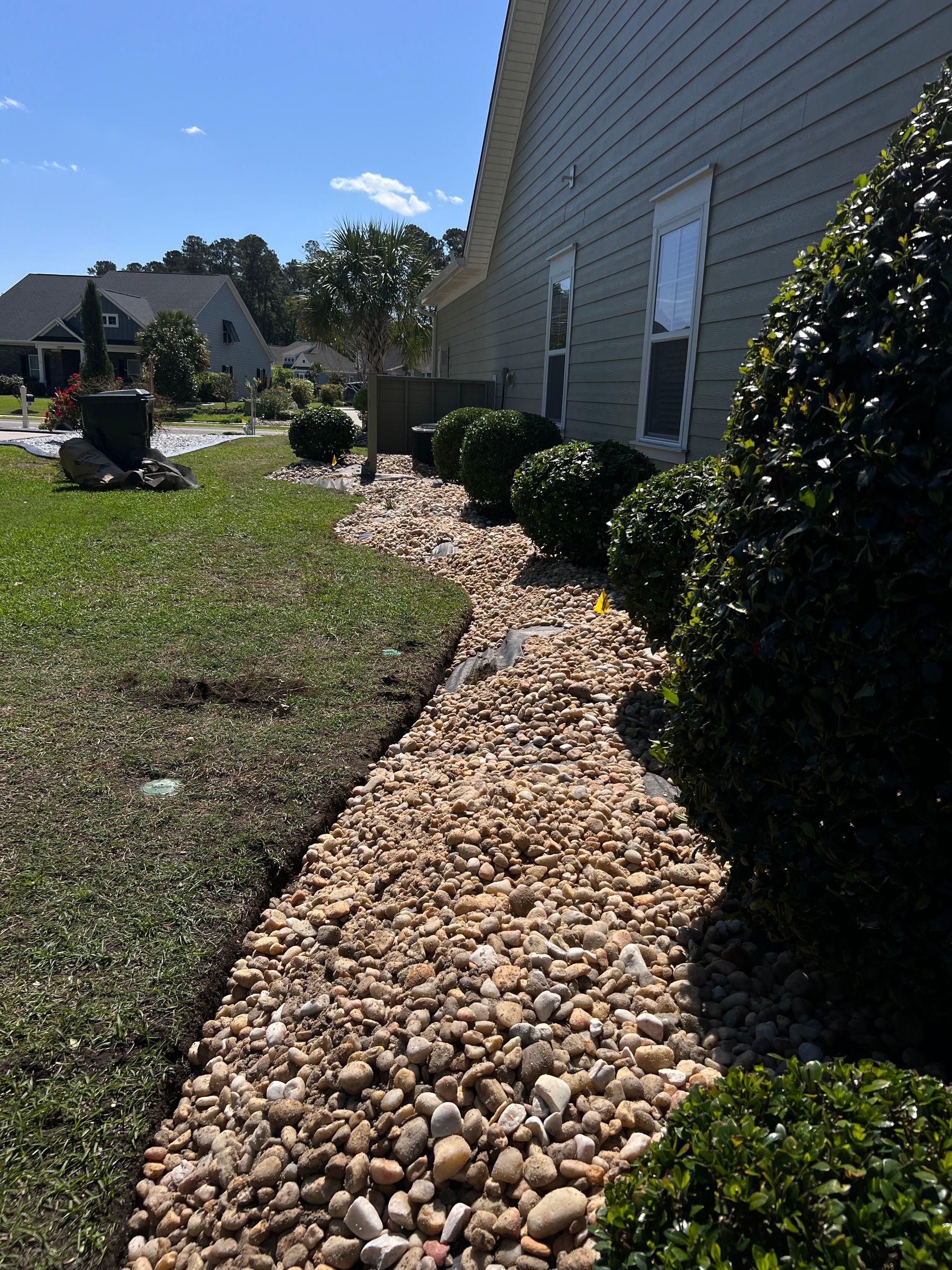 Rock bed garden border along a house beside a lawn on a sunny day