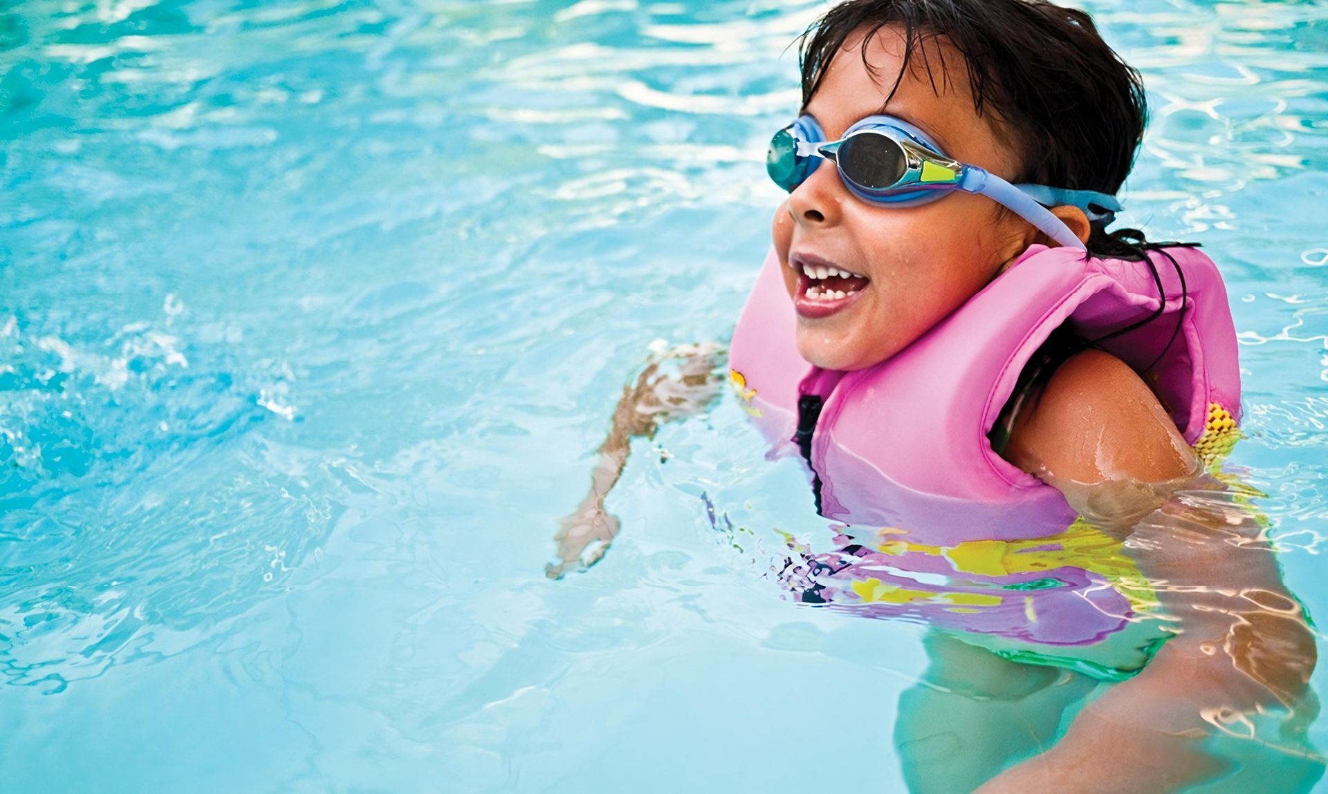 Child smiling in a pool building water confidence