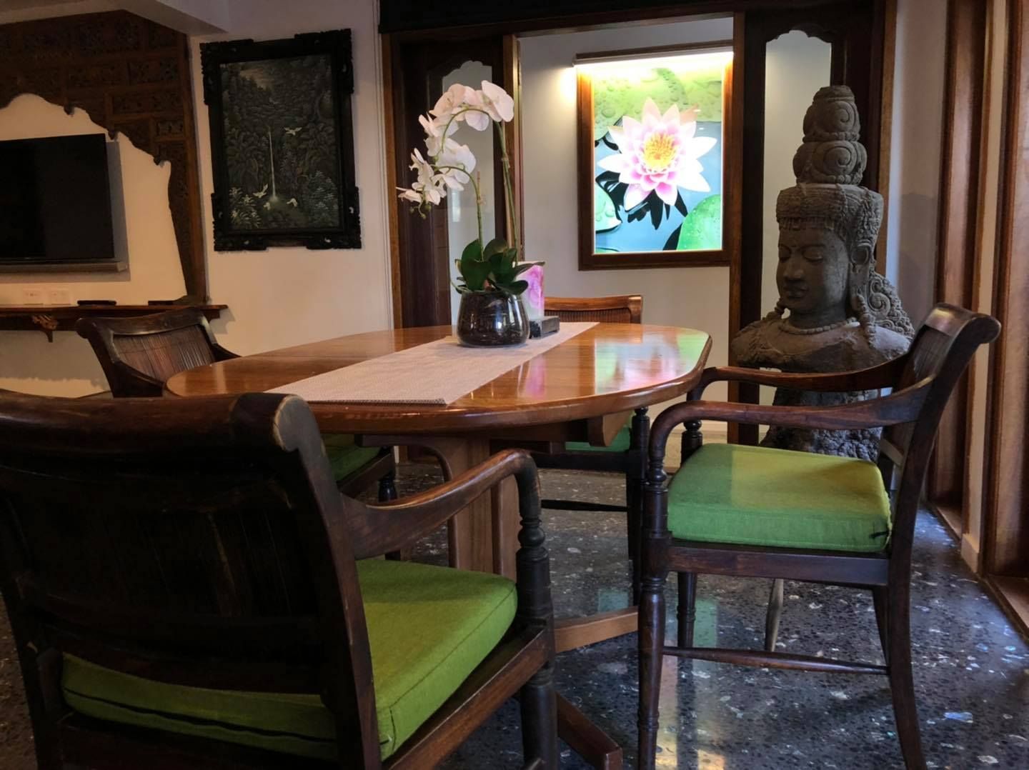 A Dining Table With Green Chairs and a Statue — Bali at the Bay in Nelson Bay, NSW