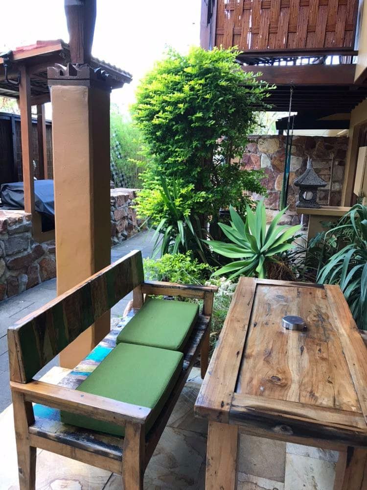A Wooden Bench and Table With Green Cushions on a Patio — Bali at the Bay in Nelson Bay, NSW