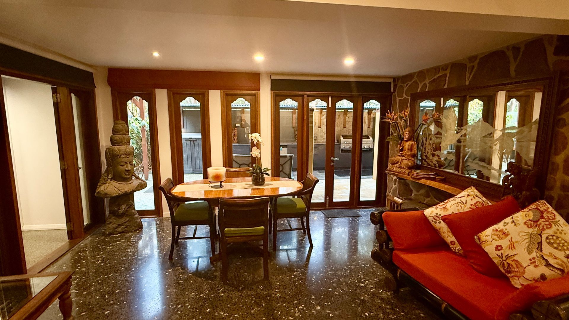 Interior of a dining room with antique furniture, statues, and large glass doors — Bali at the Bay in Nelson Bay, NSW