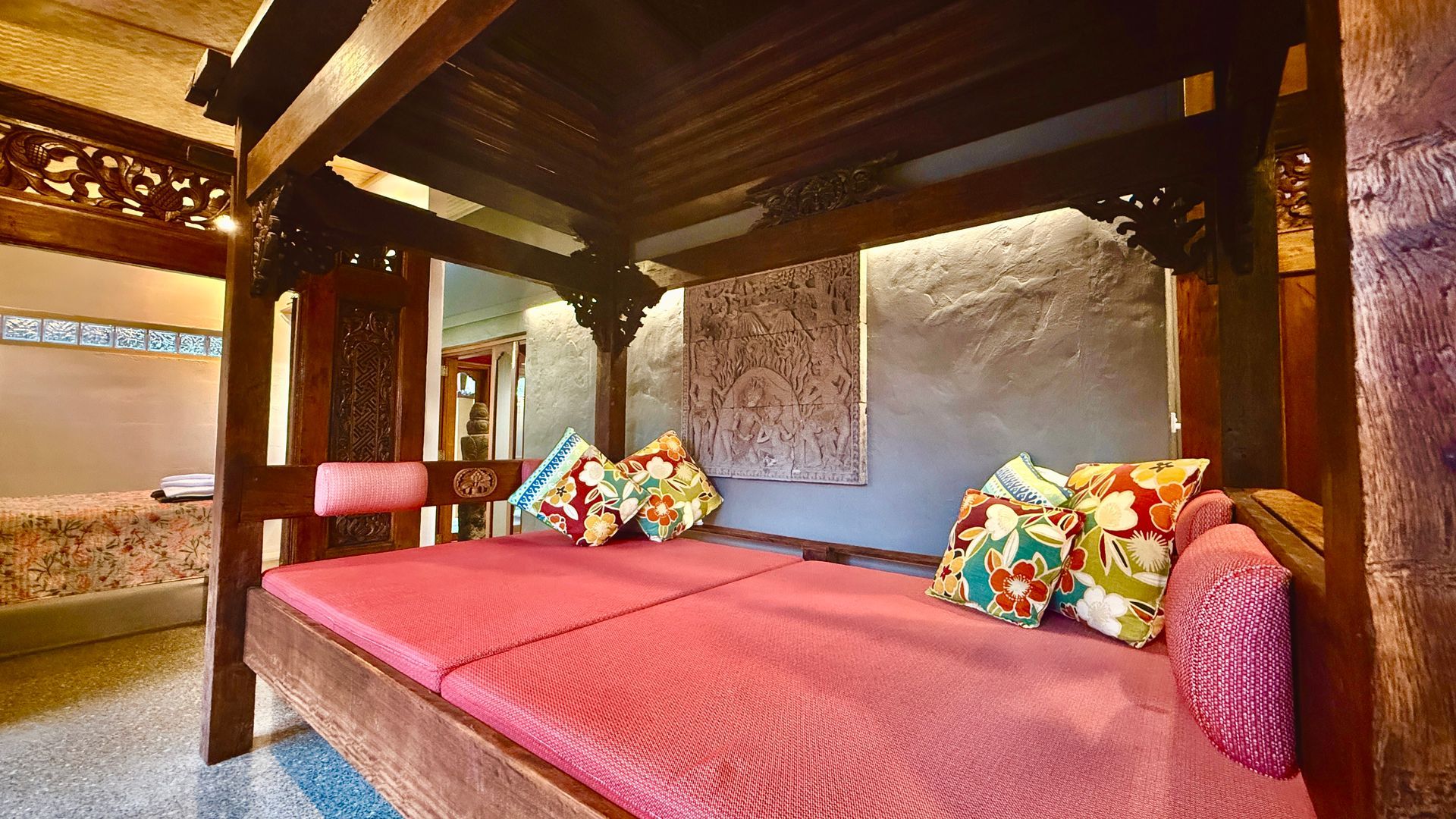 Wooden canopy bed with pink cushions and colourful pillows in a room — Bali at the Bay in Nelson Bay, NSW