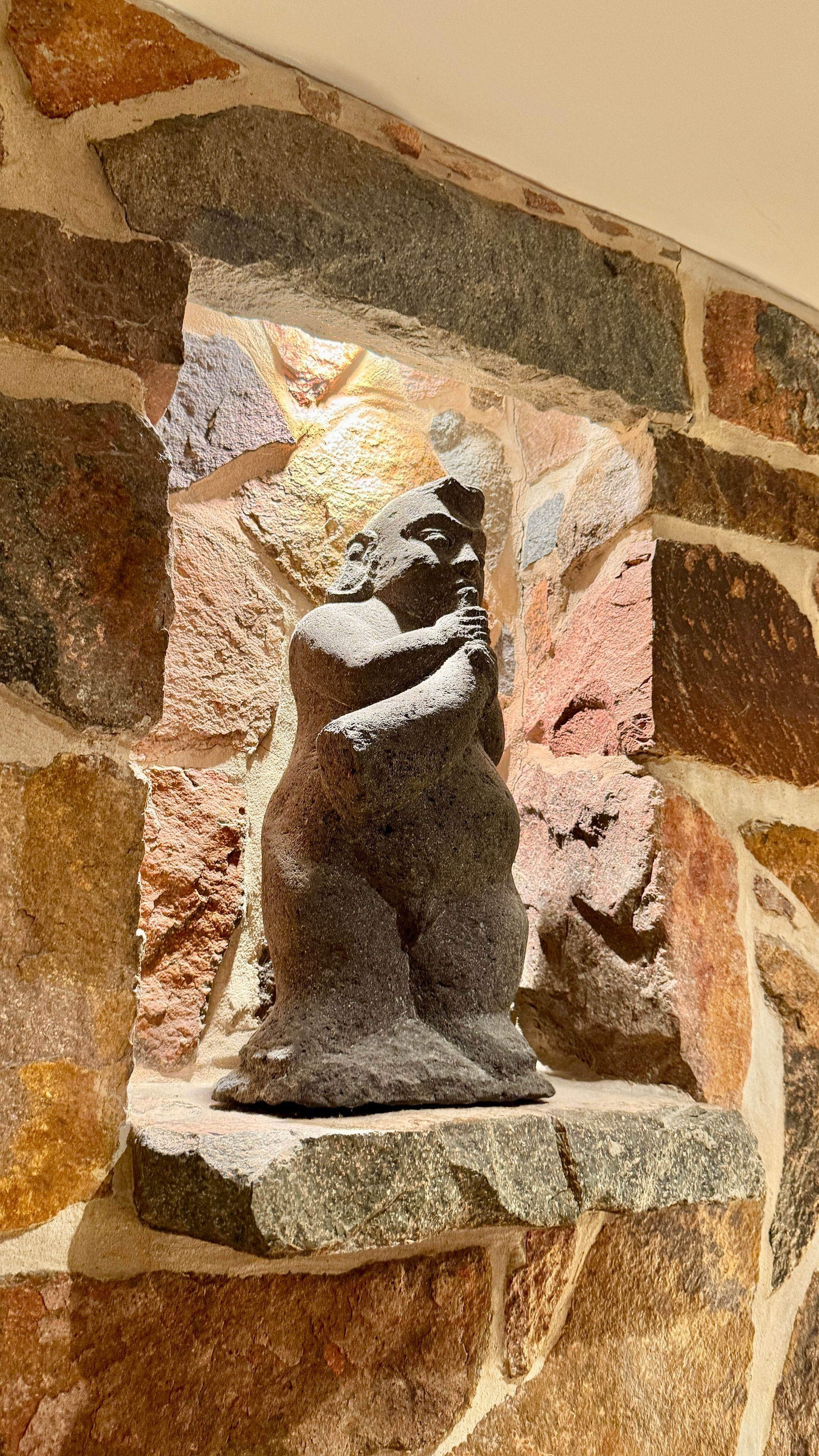 Stone statue in a recessed niche within a multi-coloured stone wall — Bali at the Bay in Nelson Bay, NSW