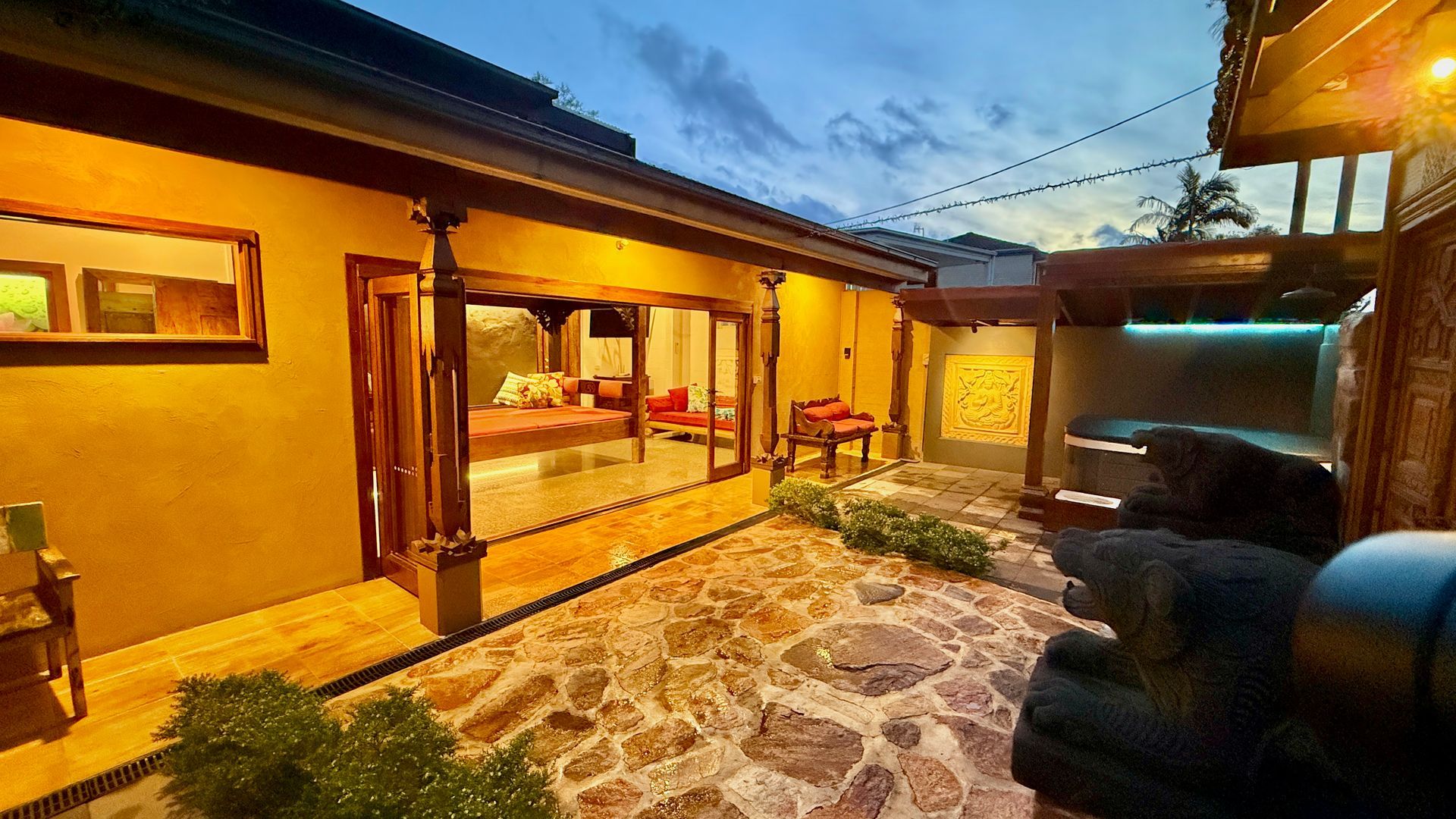 Courtyard with stone flooring, partially open house with red accents, evening sky — Bali at the Bay in Nelson Bay, NSW