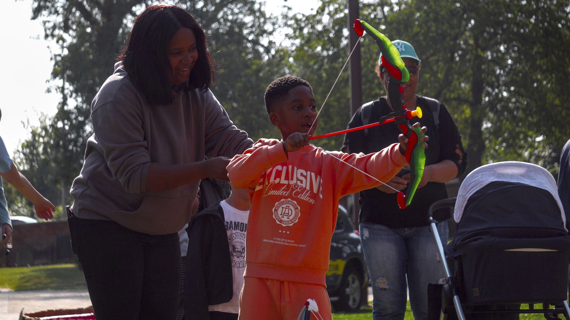A young child using a plastic bow and arrow at an event.