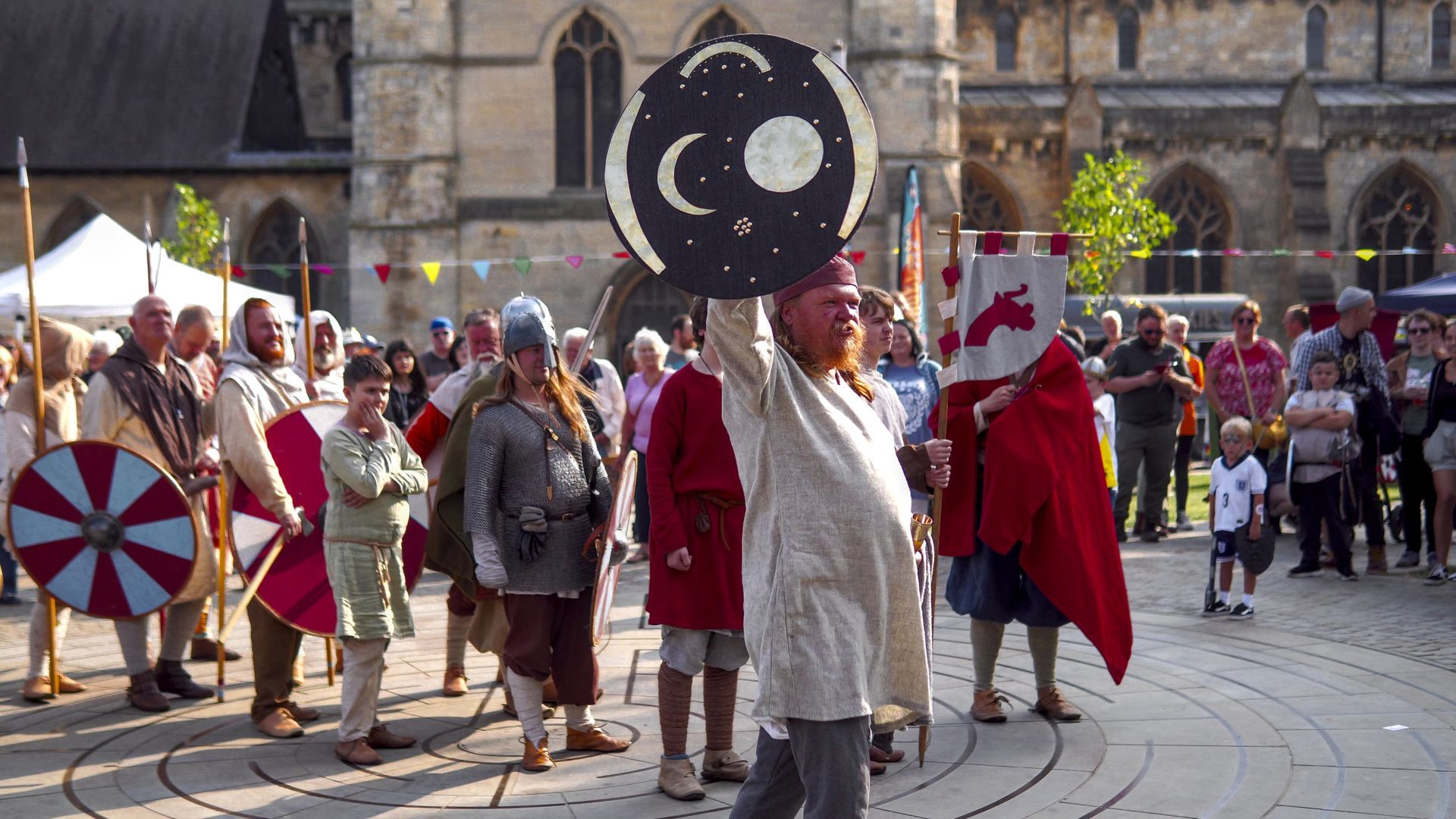 A man is holding a shield in front of a crowd of people.