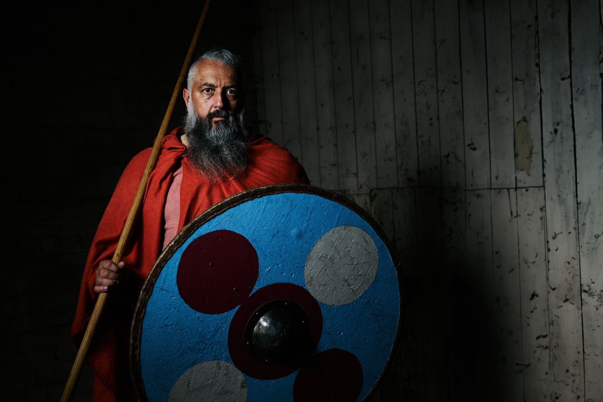 A man with a beard is holding a pole and a shield.