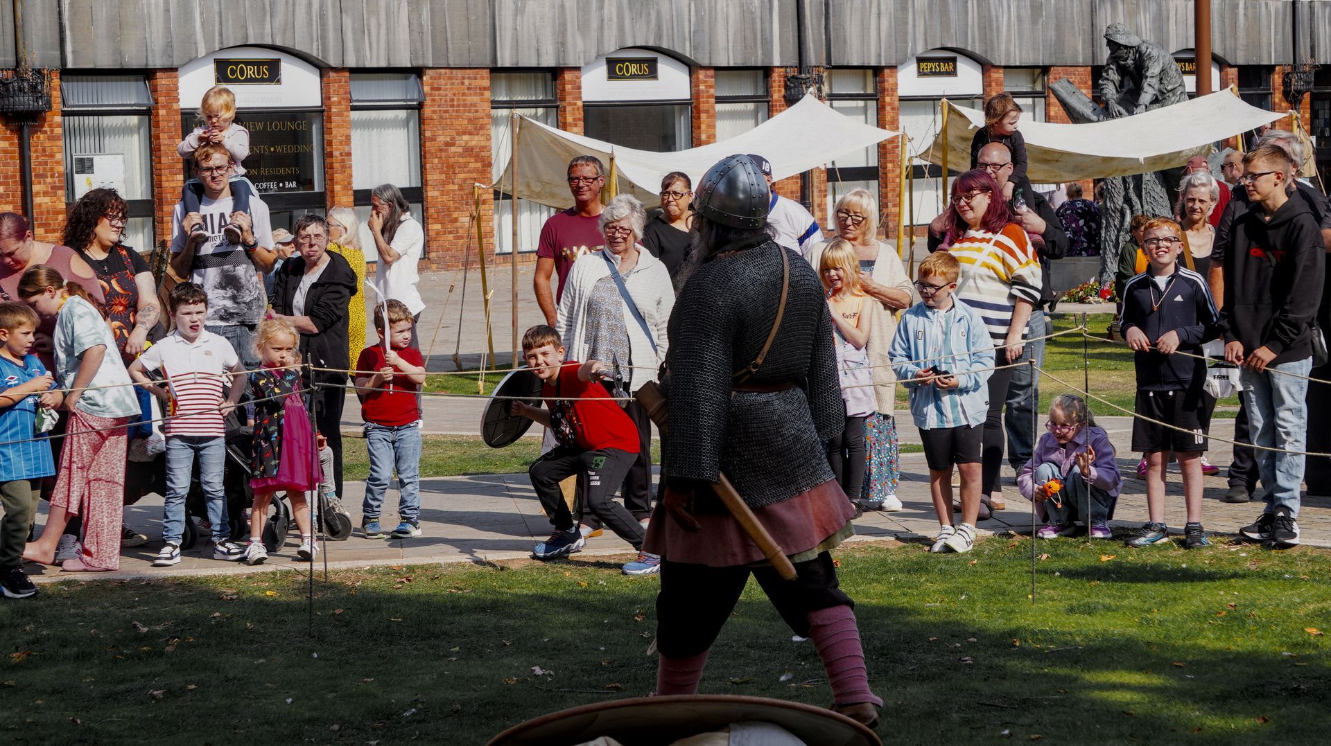 A man in a medieval costume is standing in front of a crowd of people.