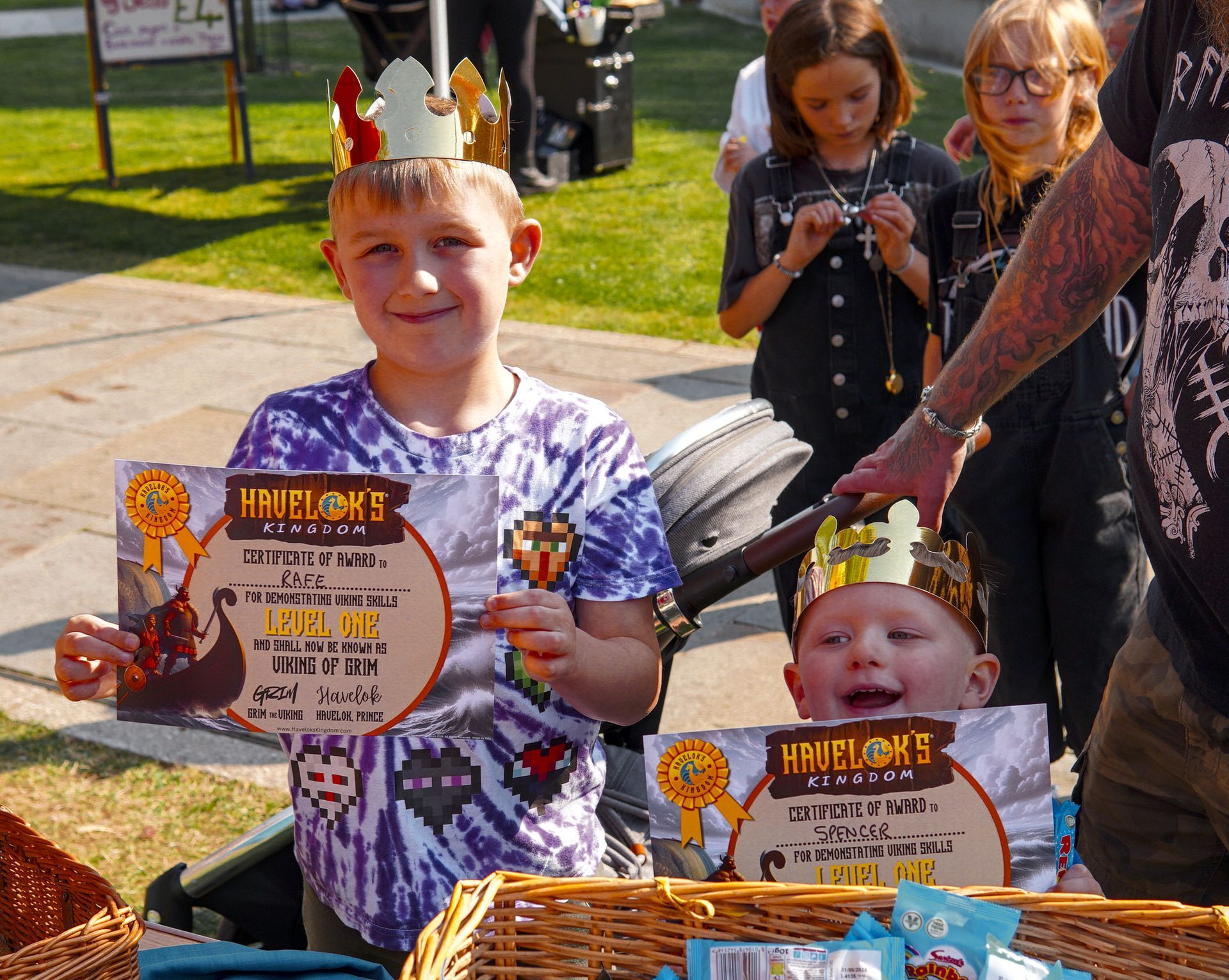 Two young boys wearing crowns are holding signs that say hmplions