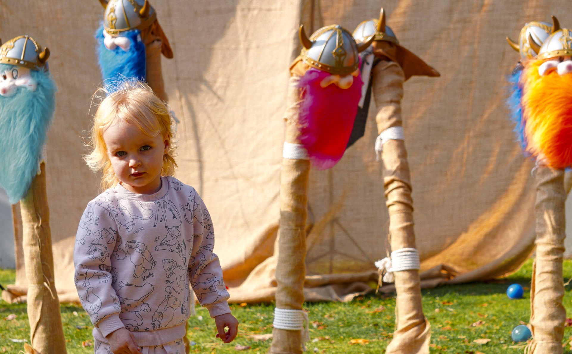 A little girl is standing in front of a bunch of stuffed vikings