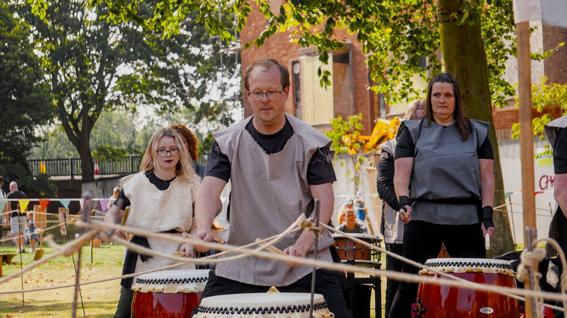 A group of people are playing drums in a park.