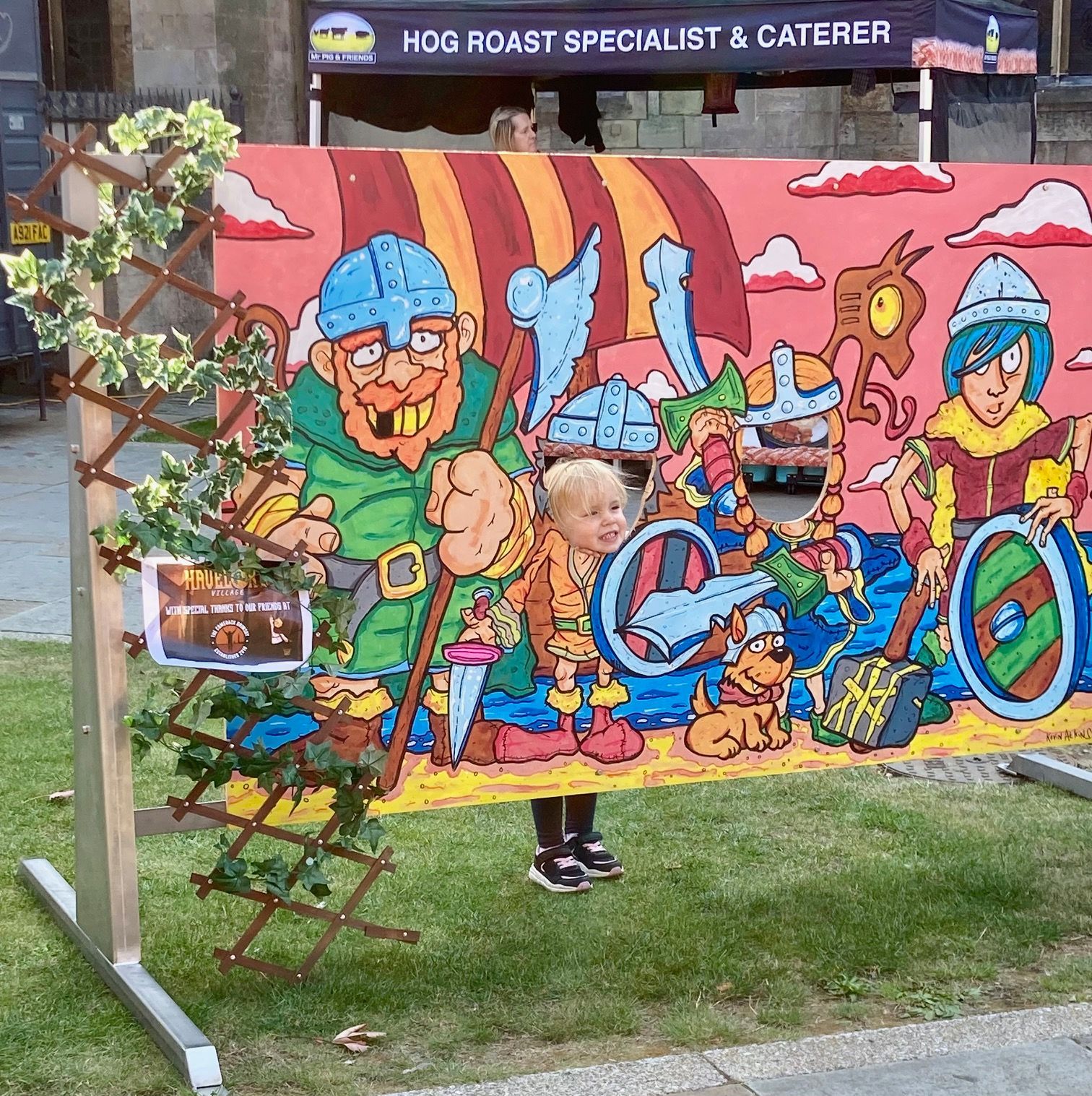 A child is standing in front of a cartoon drawing of vikings