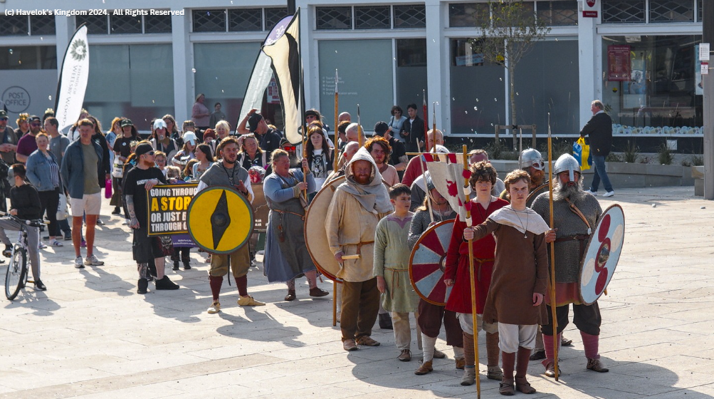 A group of people dressed in medieval costumes are walking down a street.