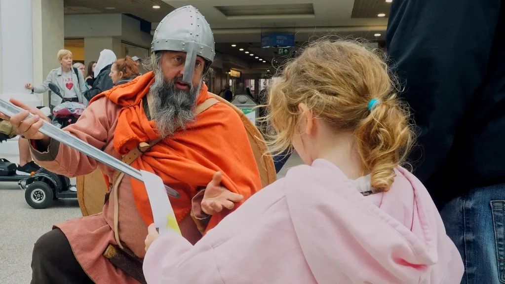 A viking kneeling to a young child at an event.