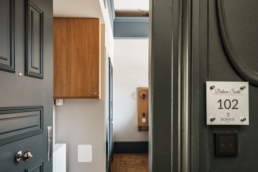Open doorway to a room with wood cabinet, light walls, and a room number 102 plate.
