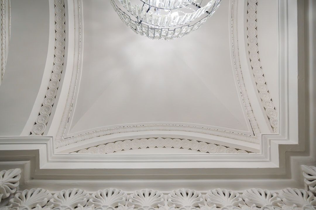 Ornate white ceiling with a crystal chandelier hanging down.