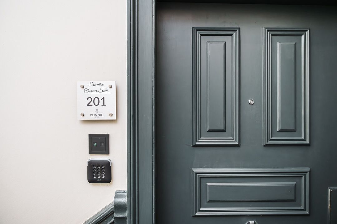 Gray door with white room number 201 plaque and keypads.