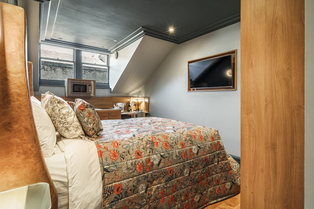 Bedroom with bed, floral comforter, TV, and window.